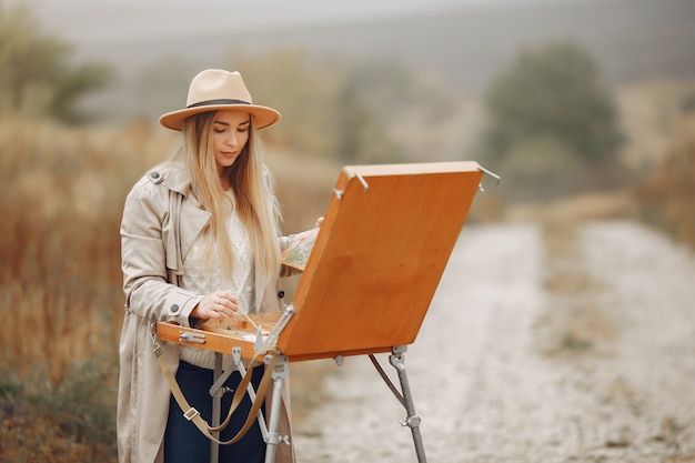 Woman in a brown coat painting in a field