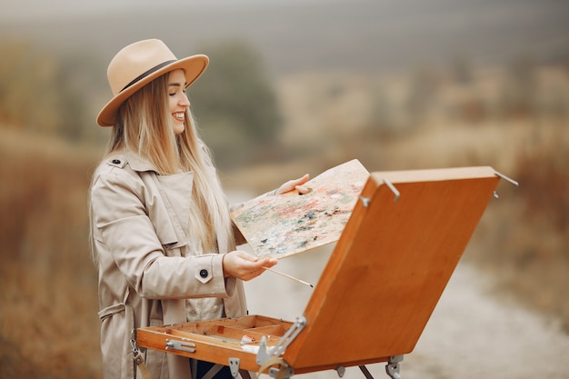 Woman in a brown coat painting in a field