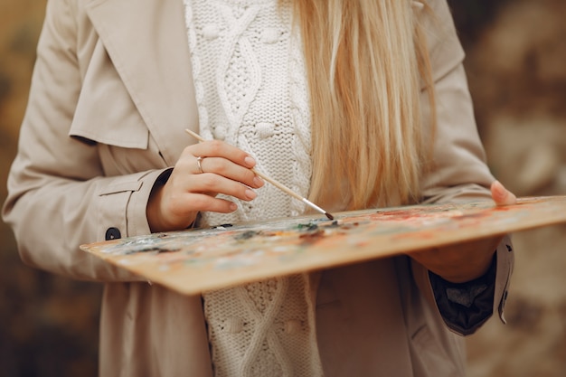 Donna in una pittura del cappotto marrone in un campo