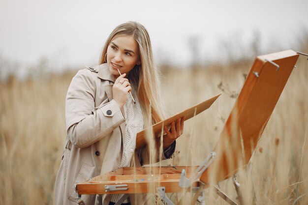 Woman in a brown coat painting in a field