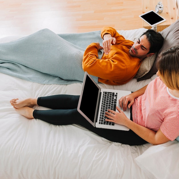 Woman browsing laptop near displeased man