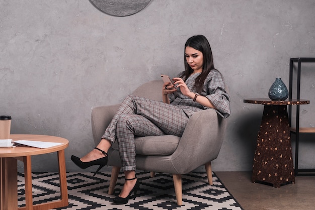 Free photo woman browsing smartphone in armchair