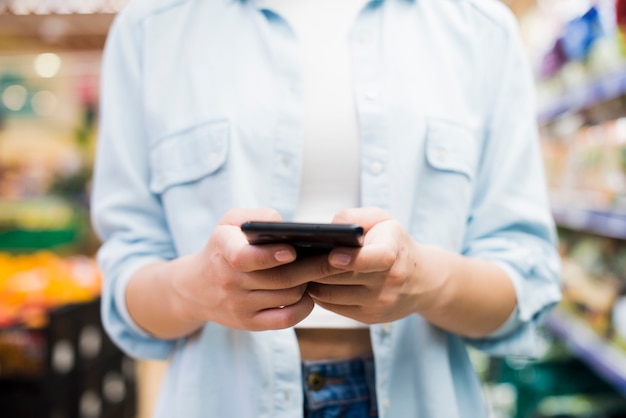 Woman browsing smartphone in grocery store