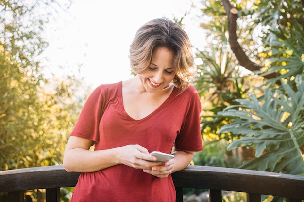 Woman browsing smartphone near fence