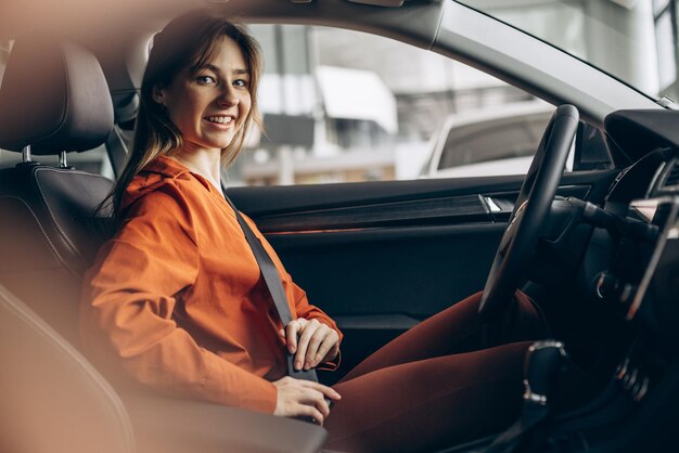 Woman buckles up the safety belt in a car