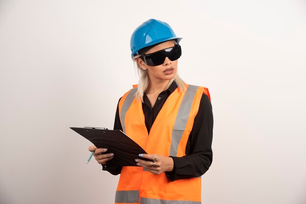 Woman builder with goggles and clipboard . High quality photo