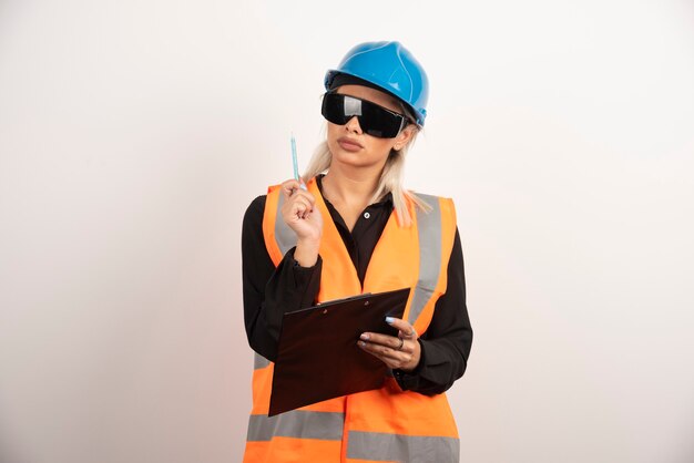 Woman builder with goggles and clipboard . High quality photo