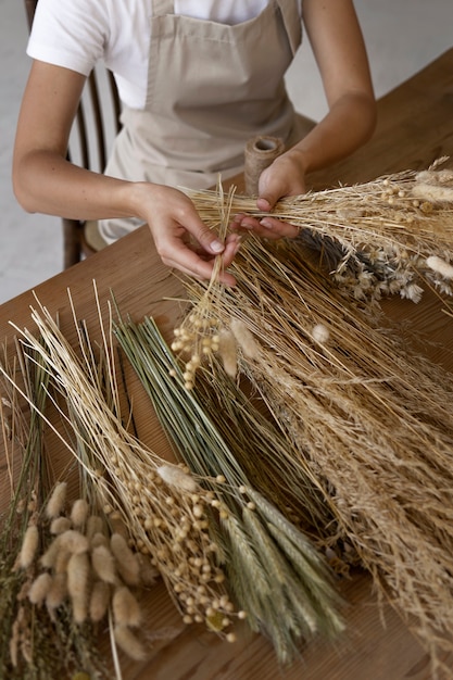 Foto gratuita donna che costruisce la propria composizione di fiori secchi