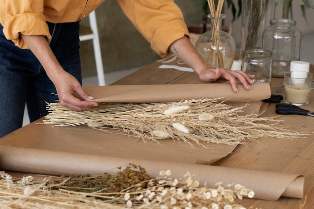 Foto gratuita donna che costruisce la propria composizione di fiori secchi