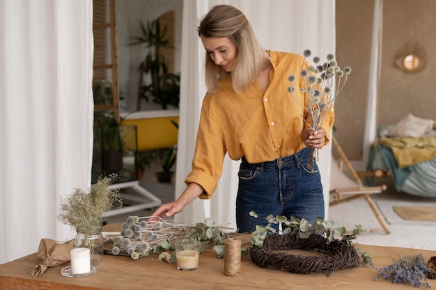 Foto gratuita donna che costruisce la propria composizione di fiori secchi