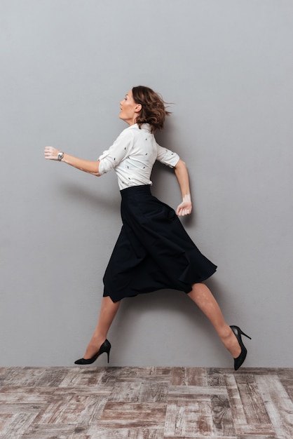 Free photo woman in business clothes running in studio.