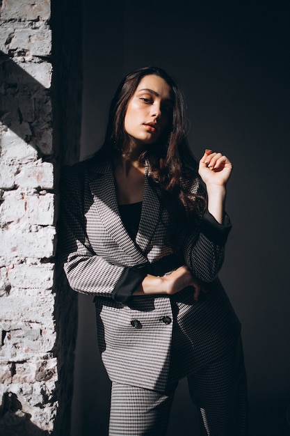 Woman in a business suit by the brick wall