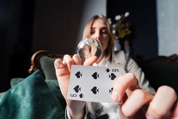 Woman in business suit holding crystal ball and six spade in her hands