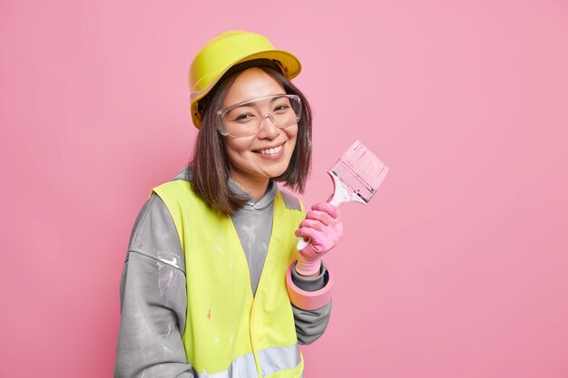 woman busy with refurbishment and renovation wears safety clothes holds painting brush 