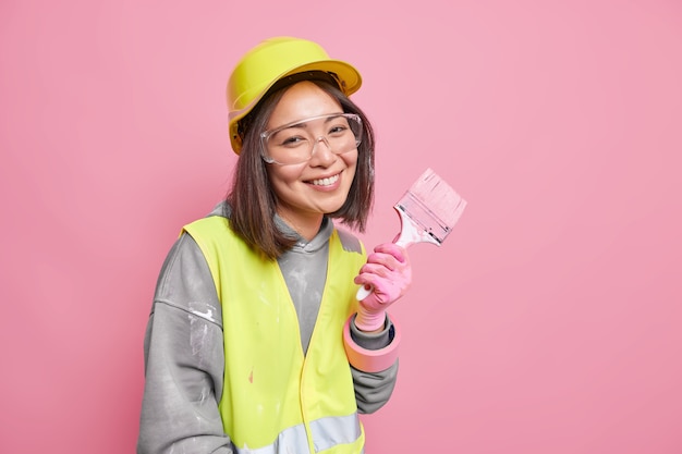 woman busy with refurbishment and renovation wears safety clothes holds painting brush 