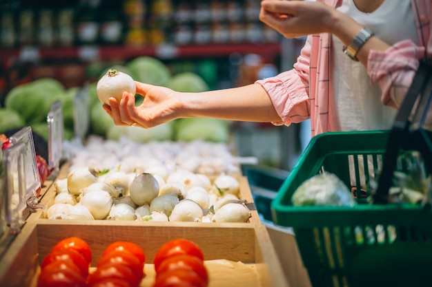 Женщина покупает в продуктовом магазине