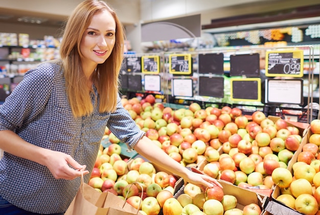 Женщина покупает спелые и вкусные яблоки