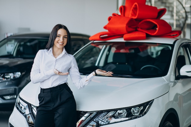 大きな赤い弓を持つ車のそばの女性