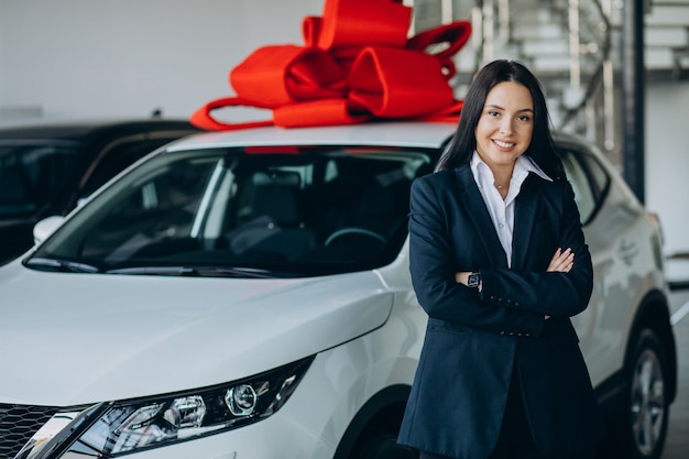 Woman by the car with big red bow