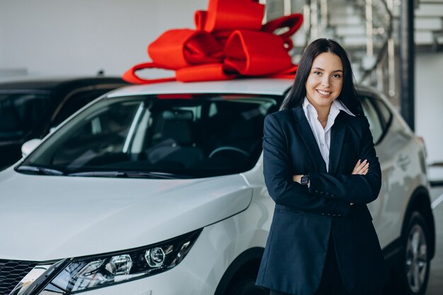 大きな赤い弓を持つ車のそばの女性