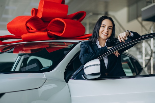 大きな赤い弓を持つ車のそばの女性