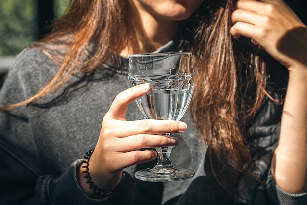 Una donna in un caffè tiene un bicchiere d'acqua in mano