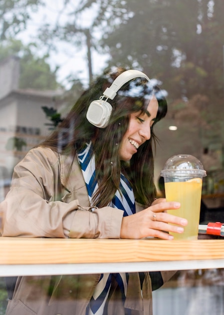 新鮮なレモネードとヘッドフォンでカフェの女性