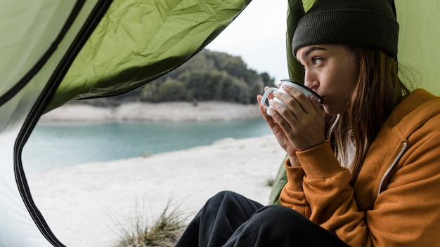 Woman camping and drinking tea sideways