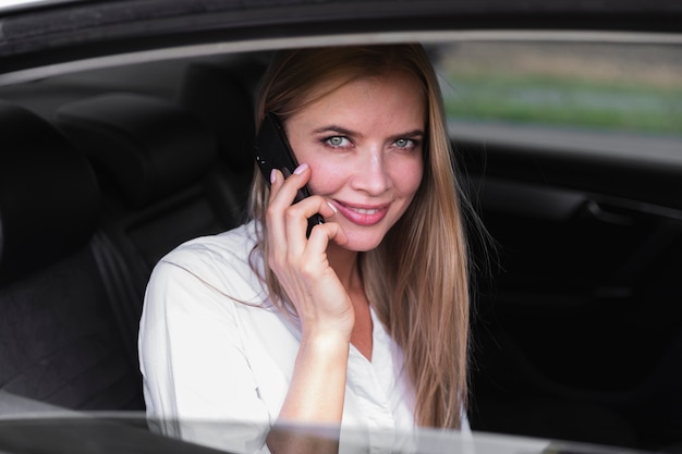 Женщина на заднем сиденье автомобиля разговаривает по телефону