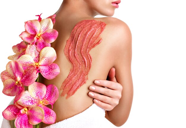 Женщина заботится о коже тела, используя косметический скраб на спине - изолированные на белом