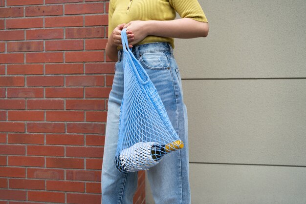 Woman carrying bottle in tote bag side view