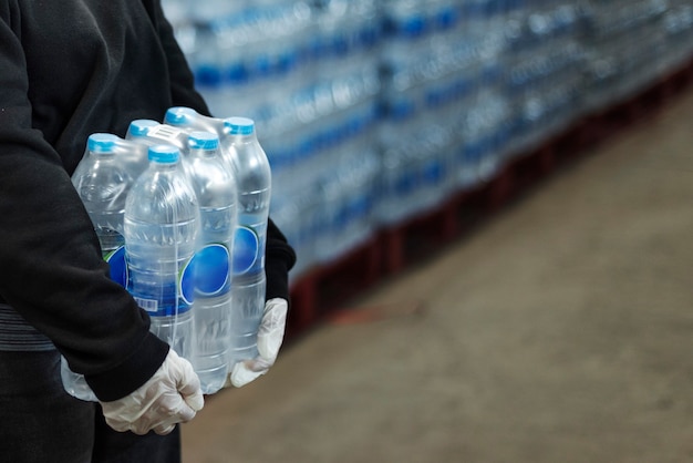コロナウイルスのパンデミック時に手袋をはめた手で飲料水を運ぶ女性