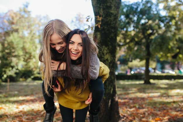 Woman carrying friend in park