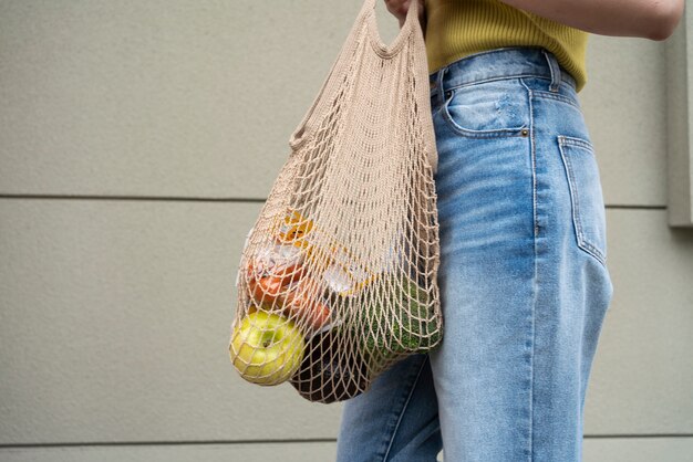 Женщина с продуктами в сумке, вид сбоку