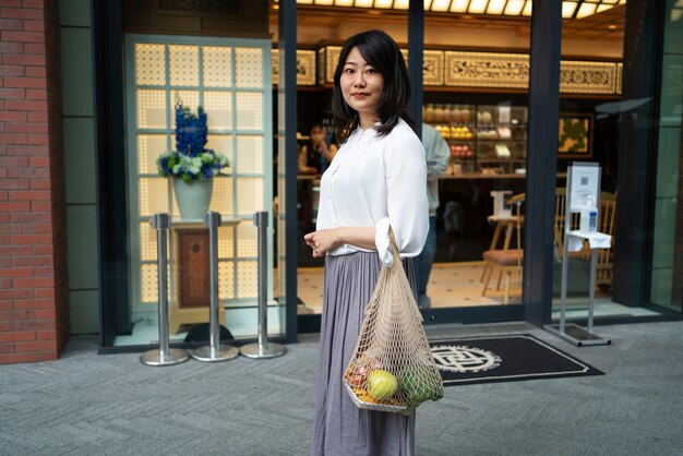 Donna che trasporta generi alimentari nella vista laterale della borsa di tote