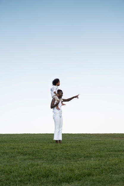 Woman carrying kid on shoulders full shot