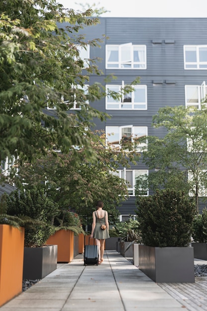 Foto gratuita donna che trasporta un bagaglio nel parco urbano