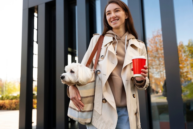 Woman carrying puppy in bag medium shot