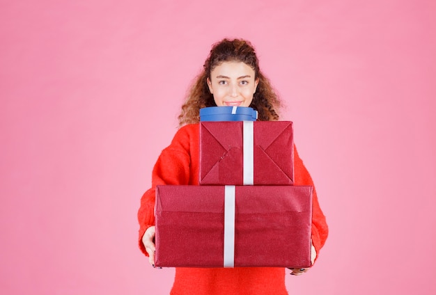 Free photo woman carrying a stock of big gift boxes.