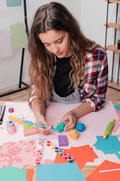 Donna che intaglia argilla colorata per fare faccia da cartone animato