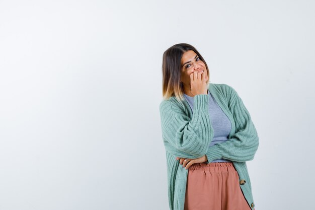 Woman in casual clothes keeping hand on chin and looking optimistic , front view.