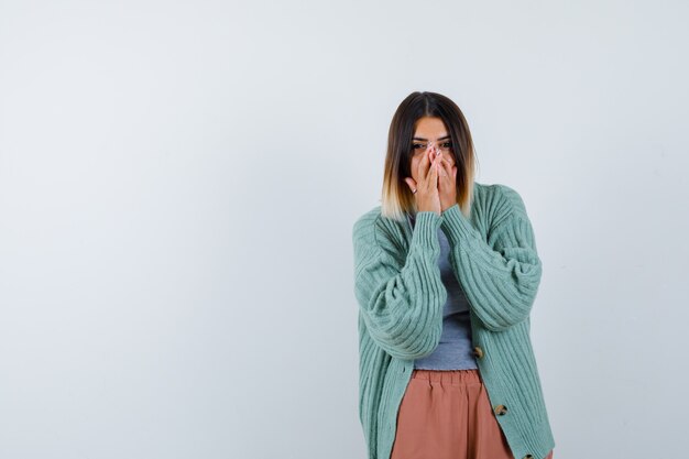 Woman in casual clothes keeping hands on mouth and looking excited , front view.