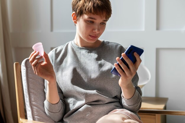 Woman on chair holding menstrual cup medium shot