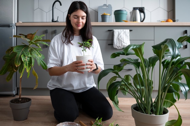 検疫中に自宅で植物の鉢を変える女性