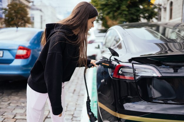 充電ステーションで電気自動車を充電する女性。