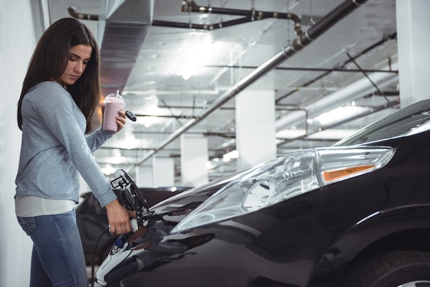 Woman charging electric car at electric vehicle charging station