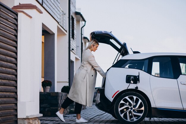 Woman charging electro car by her house