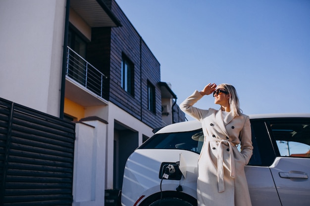 Foto gratuita donna che carica elettro automobile da casa sua