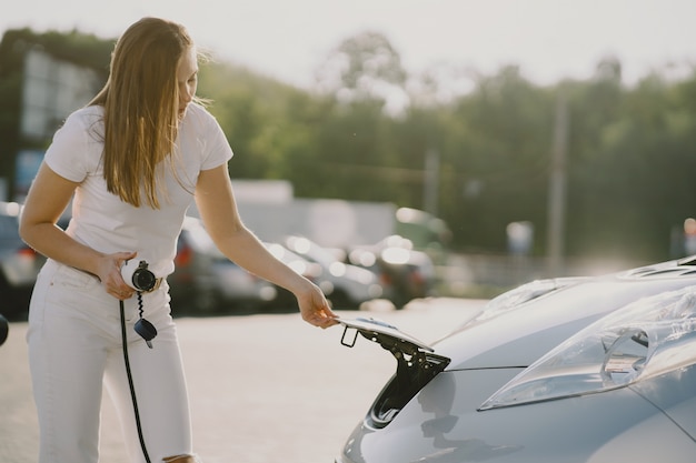 電気ガソリンスタンドで電気自動車を充電する女性