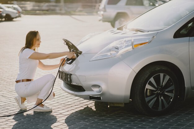 電気ガソリンスタンドで電気自動車を充電する女性